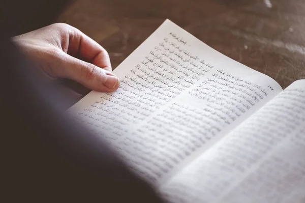 stock image A selective focus shot of a person reading an Arabic book on the table