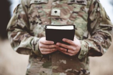 A shallow focus shot of a young soldier holding a bible clipart