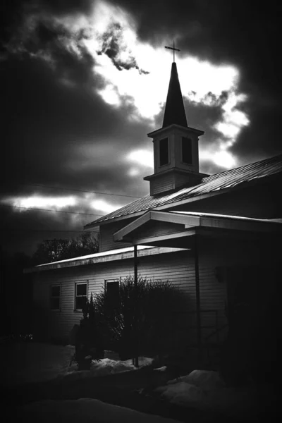 一座教堂在暴风雨云之下的一个垂直灰度的照片 — 图库照片