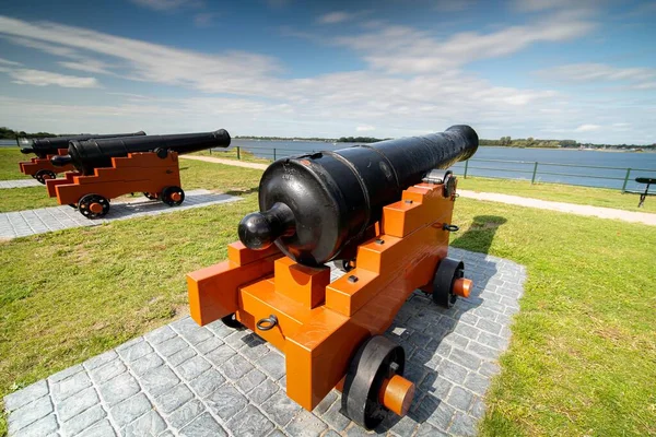 Высокоугольный Крупный План Черно Оранжевой Пушки Озером Зеленью Заднем Плане — стоковое фото