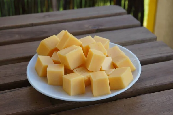Closeup Shot Gouda Cheese Blocks White Plate Wooden Surface — Stock Photo, Image