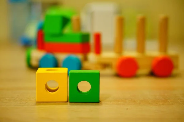 木製の表面に2つの黄色と緑の木製のおもちゃのブロックのクローズアップショット — ストック写真