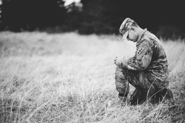 Grayscale Shot Young Soldier Praying While Kneeling Dry Grass — Stock Photo, Image