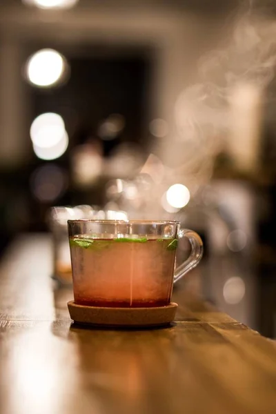 Vertical Shot Glass Herbal Tea Wooden Saucer Blurred Background — Stock Photo, Image
