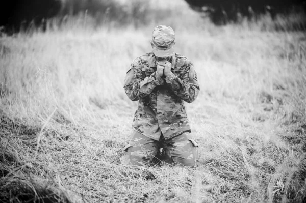 一个美国士兵跪在干枯的草地上 在田里祈祷的灰白镜头 — 图库照片
