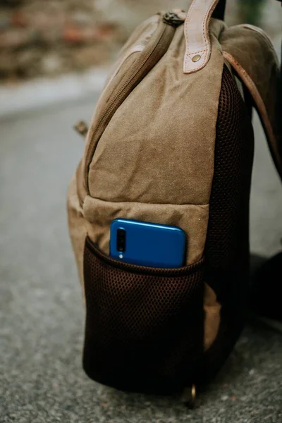 一只蓝色的智能手机插在一个棕色功能性相机袋的侧面口袋里 — 图库照片