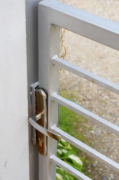 金属製のハンドルを持つ白い鉄の門の垂直閉鎖ショット — ストック写真