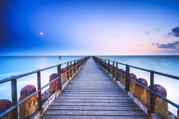 Gün Batımında Mavi Turuncu Gökyüzünün Altında Denize Açılan Ahşap Bir — Stok fotoğraf