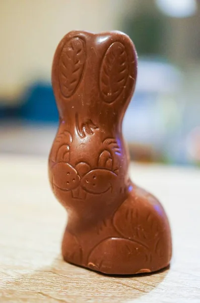 Chocolate Easter rabbit standing on a wooden surface in soft focus background.