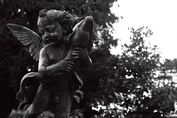 Eine Graustufen Nahaufnahme Einer Engelsstatue Umgeben Von Grün Sonnenlicht Des — Stockfoto