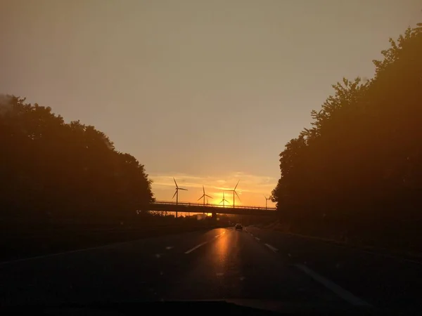 Mesmerizing View Bridge Road Surrounded Trees Wind Turbines Sunset — Stock Photo, Image