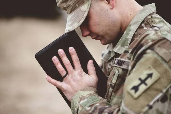一个年轻士兵拿着圣经祈祷的肤浅镜头 — 图库照片