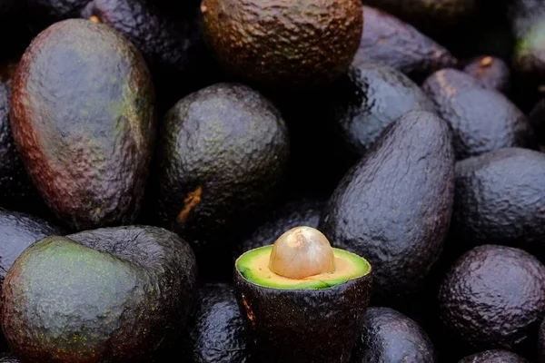 Крупный План Разрезанного Авокадо Рядом Большим Количеством Авокадо Рынке — стоковое фото