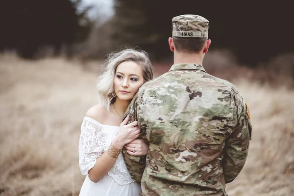 An American soldier with his loving wife standing in a dry grassy field