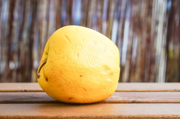 背景模糊的木制表面上一个黄色苹果的特写镜头 — 图库照片