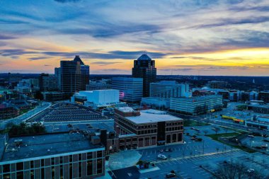 A beautiful scenery of the sunset in a cloudy sky near the Greensboro skyline clipart