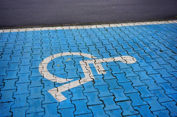 蓝色鹅卵石地面上残疾人标志的高角特写镜头 — 图库照片