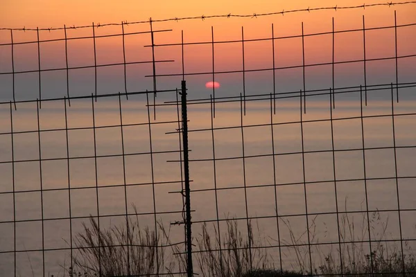 Uma Bela Foto Pôr Sol Sobre Oceano Atrás Cerca Metal — Fotografia de Stock