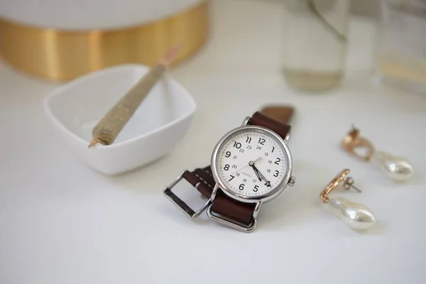 Stilvolle Uhr Mit Lederarmband Uhr Mit Cannabis Joint Auf Beistelltisch — Stockfoto