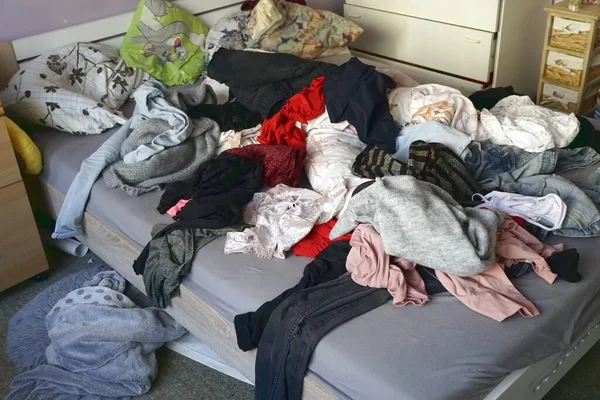 A high angle shot of a messy room with clothes scattered on the bed