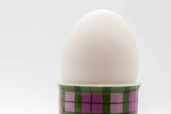 白い背景の模様のカップの中の白い卵のクローズアップショット — ストック写真