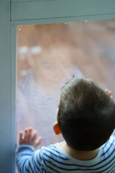 Enfant Dans Haut Rayé Regardant Par Fenêtre Par Jour Sombre — Photo