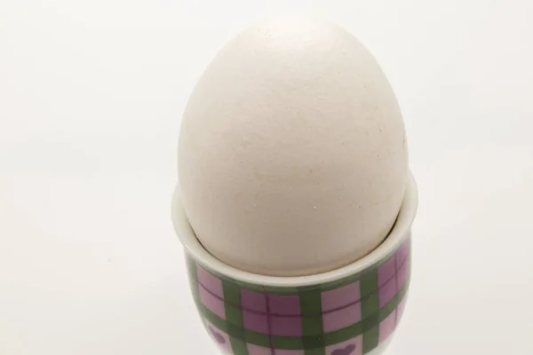 白い背景の模様のカップの中の白い卵のクローズアップショット — ストック写真