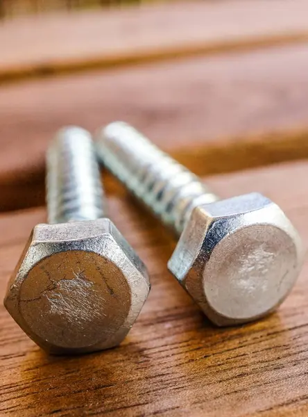 Primer Plano Vertical Dos Tornillos Plateados Sobre Una Mesa Madera —  Fotos de Stock