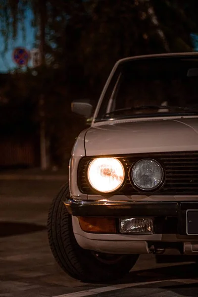 通りに円形のヘッドライトを持つ白いヴィンテージのクラシックカーの美しいショット夜 — ストック写真