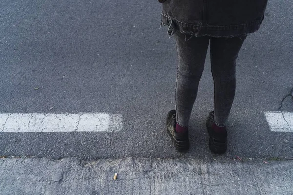 A high angle shot of a person in a black outfit standing on the sidewalk