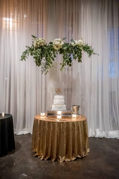 エレガントな装飾が施された小さなテーブルの上に美しい白いウェディングケーキの垂直ショット — ストック写真