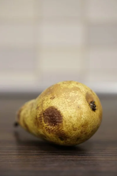 木桌上一只腐烂的黄色梨子的特写镜头 — 图库照片