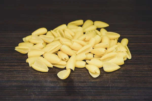 Closeup Shot Pile Raw Pasta Shells Wooden Table — Stock Photo, Image