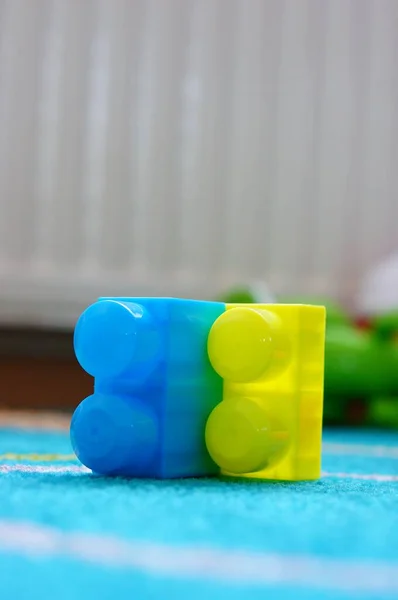 ラグの上に青と黄色のプラスチック製のおもちゃのブロックのクローズアップショット — ストック写真