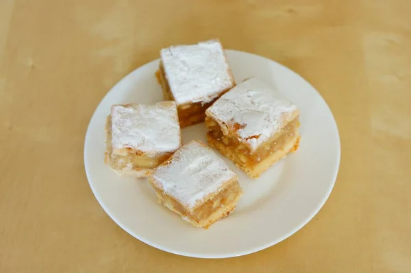 A closeup of biscuits with jam on a white plate on the wooden table under the lights