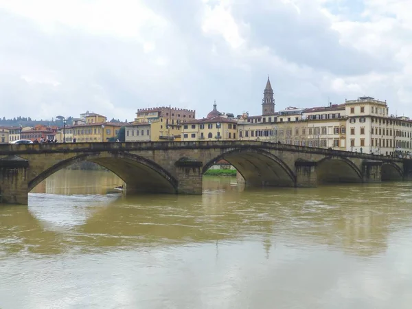 イタリアのフィレンツェの距離にある建物と水の上の橋 — ストック写真