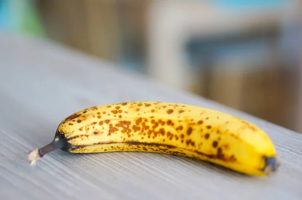 Dojrzały Banan Brązowymi Plamami Drewnianym Stole — Zdjęcie stockowe