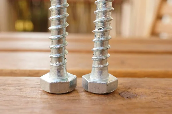 Egy Közeli Felvétel Két Ezüst Csavarral Egy Fából Készült Asztalon — Stock Fotó