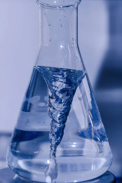 一个装有液体的实验室玻璃瓶的垂直特写镜头 — 图库照片