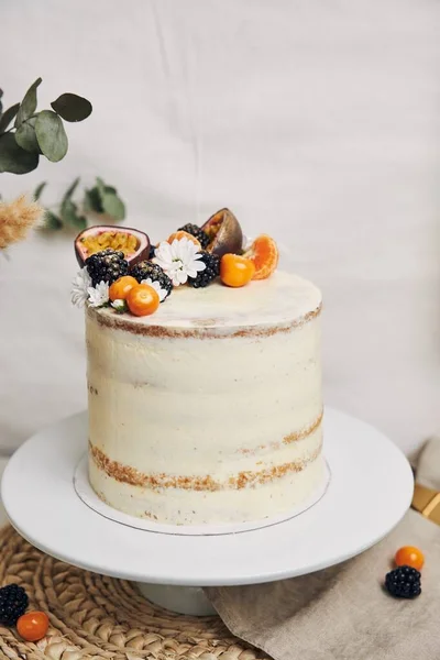 白い背景の後ろの植物の隣に果実とパッションフルーツの白いケーキ — ストック写真