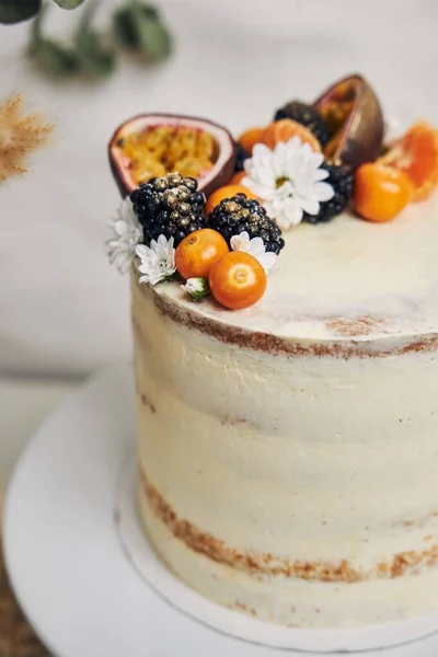 白い背景の後ろの植物の隣に果実とパッションフルーツの白いケーキ — ストック写真