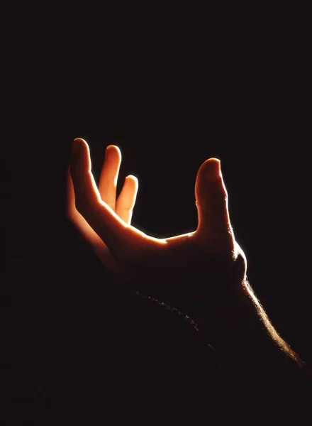 黒い背景の人の手の垂直ショット — ストック写真