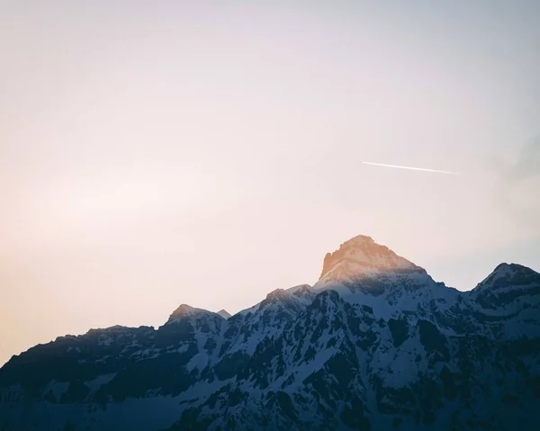 꼭대기에 햇빛이 내리쬐는 눈덮인 — 스톡 사진