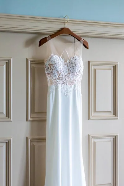 花嫁の部屋のドアにかかっている美しい白いウェディングドレスの垂直ショット — ストック写真
