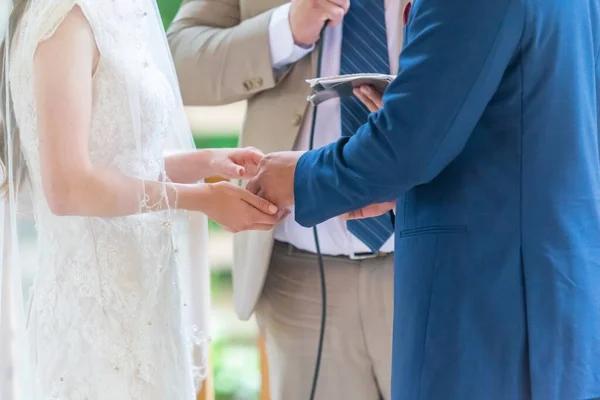 豪華な白いドレスを着た花嫁と司祭との結婚式中の青いスーツの新郎 — ストック写真