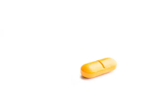 白色表面上一颗黄色药丸的特写镜头 — 图库照片