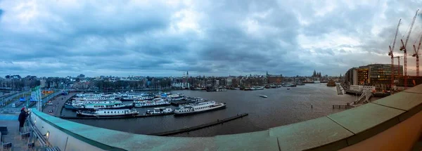 在乌云密布的阿姆斯特丹 一个有很多船只的港口的全景照片 — 图库照片