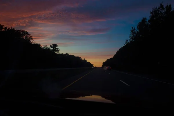 Ένας Αυτοκινητόδρομος Αυτοκίνητα Επενδεδυμένα Δέντρα Κάτω Από Ένα Πολύχρωμο Ηλιοβασίλεμα — Φωτογραφία Αρχείου
