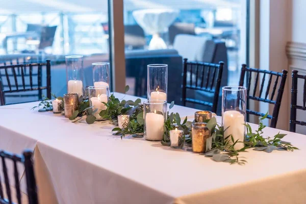 エレガントなキャンドルと緑の葉を持つ白いテーブルの高角度ショット — ストック写真