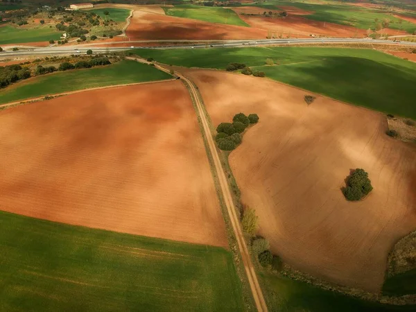 空中拍摄的农田穿过了一条在公路上结束的公路 — 图库照片